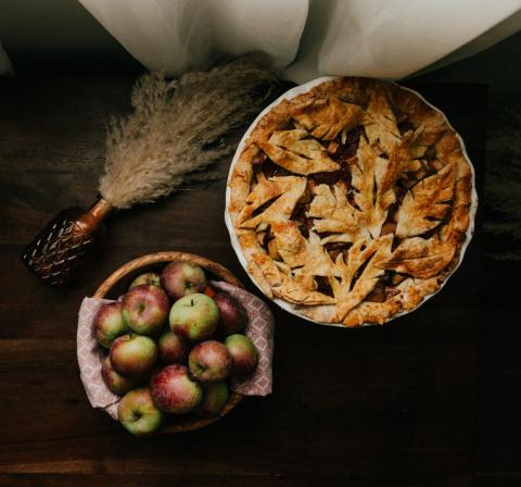 November 2021 photo writing prompt_fall table setting of fresh red and green apples in a basket beside a beautiful apple pie by Priscilla DuPreez via Unsplash