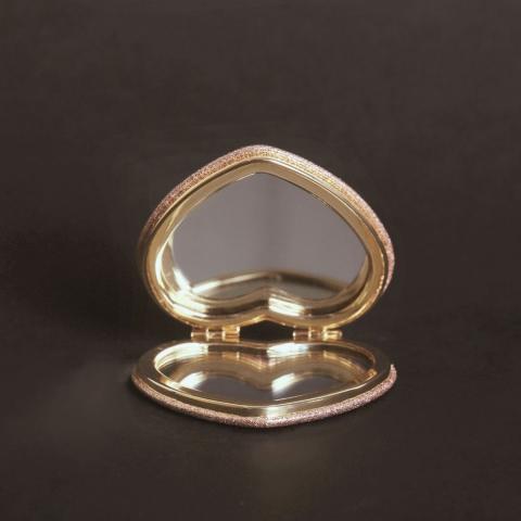 small rose gold heart-shaped compact mirror on black surface
