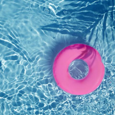 round pink tube floatie in a blue pool on a sunny day