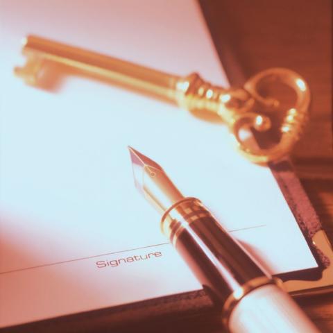 a gold skeleton key and a fountain pen resting on a blank page with a signature line at the bottom via Canva