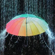 colorful umbrella suspended in the air with torrential rain all around