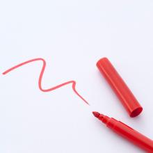 red pen with cap off and a wavy line drawn on white paper via Canva